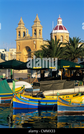 Harbour with Luzzu fishing boats and Marsaxlokk Parish Church, Marsaxlokk, Malta, Mediterranean, Europe Stock Photo