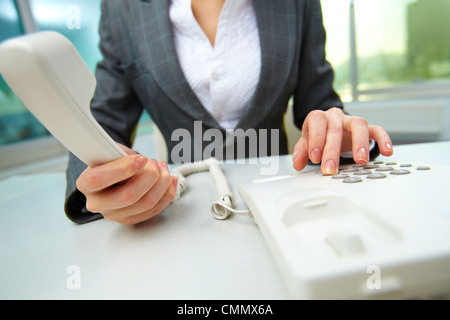 Female hands holding phone receiver and dialing number Stock Photo