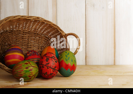 Six painted Easter eggs came out of the rattan basket. Isolated with Shabby chic white wooden background Stock Photo