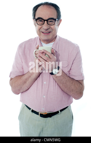 Smiling old man holding a coffee mug posing in front of camera Stock Photo