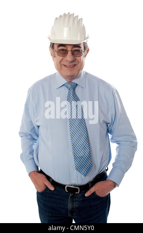 Aged builder posing with arms in pocket, smiling on white background Stock Photo