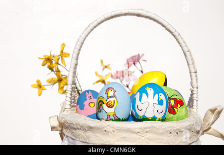 Wicker basket with Colorful hand painted Easter eggs, against light background Stock Photo