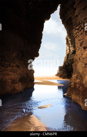 a view from the inside of a beach cave looking out at the sea Stock Photo