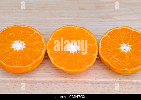 Studio shot of three Clementine orange halves, which are a variety of mandarin orange, displayed on a chopping board Stock Photo
