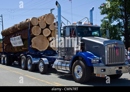 USA, Washington, Forks. Logging trucks with old growth logs in parade; Independence Day, 4th of July. Stock Photo