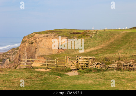 South West Coast Path (SWCP)  and kissing gate on Maer Downs cliffs with view to GCHQ satellite dishes Bude Cornwall England UK Stock Photo