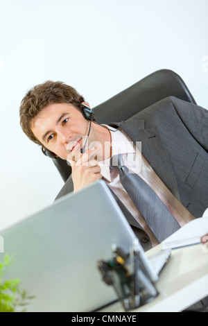 Thoughtful modern businessman with headset working on laptop Stock Photo