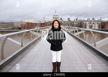 Smiling East Asian Woman at Millennium Bridge, St Paul's Cathedral in the distance. Stock Photo
