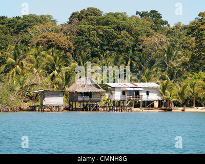 Rustic houses on stilts on the sea shore with lush tropical vegetation in background, Bocas del Toro, Panama, Central America Stock Photo