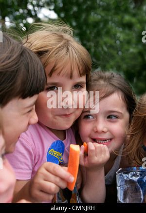 Girls eating raw carrots in Hyde Park London Stock Photo