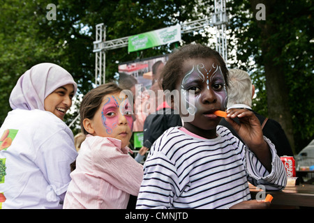 Children with face paints eating raw carrots in Hyde Park London Stock Photo