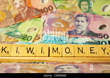 New Zealand Currency and Scrabble tiles spelling out the words Kiwi Money. Stock Photo