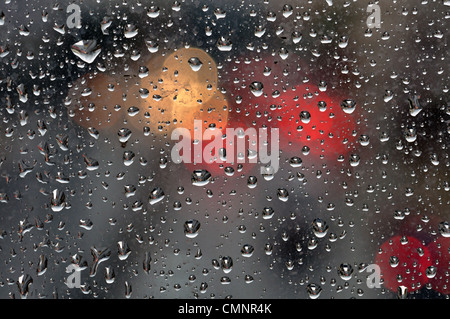 Raindrops on glass surface and blurry abstract city lights. Background texture. Stock Photo