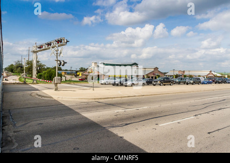 Cars waiting at intersection for train to pass 'Hill Country Flyer' tourist train in Cedar Park, Texas (suburb of Austin). Stock Photo