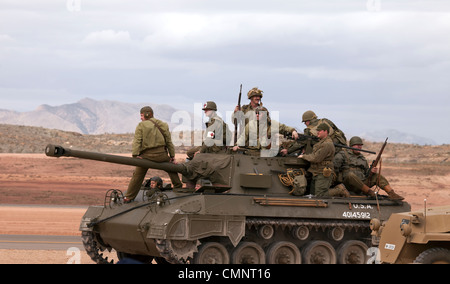 Army troops riding on top of vintage antique World War II US tank during a display in desert setting. Stock Photo