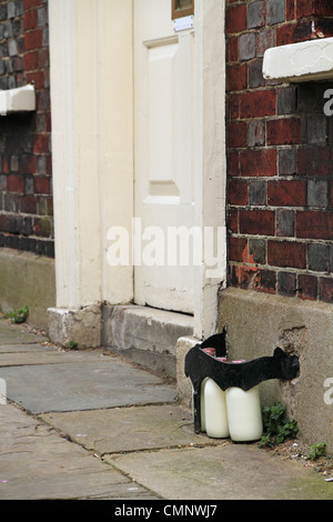 Glass bottles of delivered fresh milk on the street outside the front door of a house in Lewes, East Sussex, England. Stock Photo