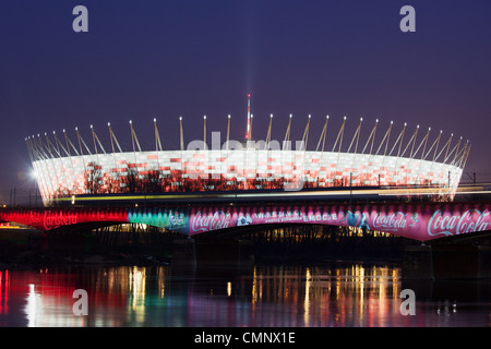 National Stadium illuminated at dusk and Srednicowy Bridge by the Vistula river in Warsaw, Poland Stock Photo