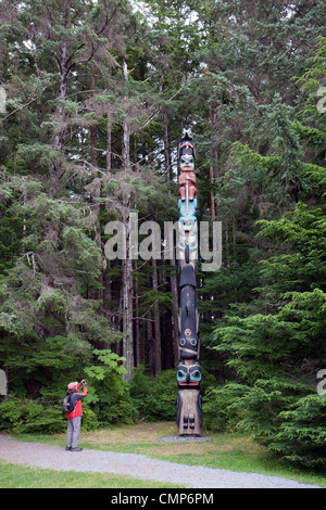 Woman photographing a totem pole in Sitka National Historical Park, Sitka, Alaska, USA. Stock Photo