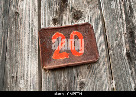 Number twenty on metal plate attached to wooden background Stock Photo