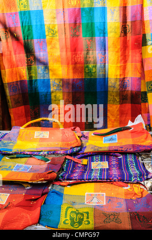 Brightly colored woven textiles for sale at the market stalls selling local souvenirs and handicrafts to tourists visiting Chichen Itza Mayan ruins archeological site in Mexico. Stock Photo