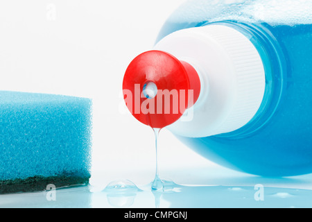 dish washing liquid flows out of the bottle, blue sponge on white Stock Photo