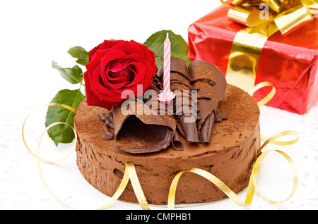 Celebrating birthdays with delicious toffee cake, red rose and gifts. Isolated on white background. Stock Photo