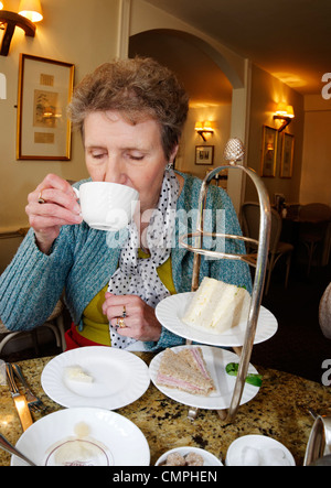 An elderly lady drinking tea in Betty's Cafe, York Stock Photo