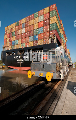 Container cargo ship and locomotive at Miraflores Locks. Panama Canal Stock Photo