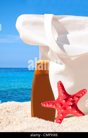 Beach bag, sun cream and starfish on tropical beach - Holiday concept  Stock Photo