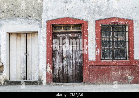 Colonial Architecture Doorways Valladolid Mexico | VALLADOLID, Mexico — Weathered doorways and a barred window line a facade in the centro histórico of Valladolid, a Spanish colonial town on the Yucatan Peninsula. Founded in 1543 by conquistador Francisco de Montejo atop the Maya city of Zaci, Valladolid preserves colonial-era buildings dating from the 16th through 19th centuries. Peeling plaster and wrought-iron grillework reflect the tropical climate's toll on centuries-old masonry. Stock Photo