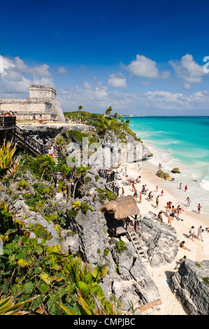 El Castillo Pyramid Overlooking Beach Caribbean Coast Tulum Mexico // TULUM, Mexico — El Castillo pyramid overlooks the Caribbean coastline at the ancient Maya archaeological site of Tulum. The Tulum ruins, perched on 12-meter (39-foot) limestone cliffs, served as a major trading port for the Maya civilization from approximately 1200 to 1450 CE. This walled coastal city was among the last Maya settlements to be inhabited when Spanish conquistadors arrived in the early 16th century. The archaeological site combines ancient limestone temples and structures with white sand beaches along Mexico's  Stock Photo