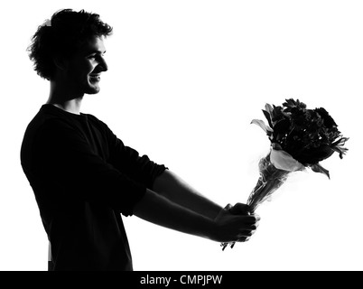 young man offering flowers bouquet silhouette in studio isolated on white background Stock Photo