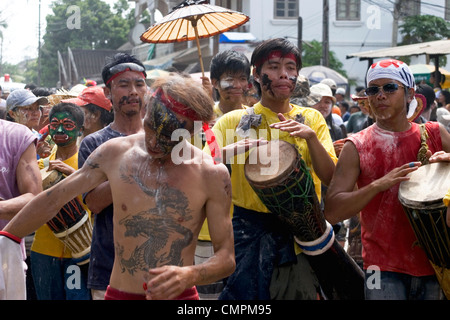 A man with a dragon tattoo is marching in a parade on a city street during the Lao New Year celebration in Luang Prabang, Laos. Stock Photo