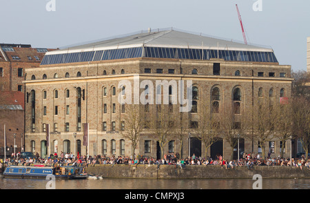 People enjoy the sun on the harbourside outside the Arnolfini gallery in Bristol. The centre is a cultural hotspot for the city. Stock Photo