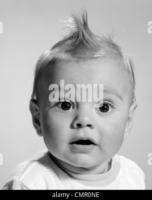 1960s CLOSE-UP PORTRAIT BABY WITH WIDE-EYED EXPRESSION WITH MOUTH OPEN LOOKING AT CAMERA Stock Photo