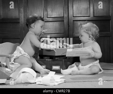 1960s TWO BABIES WEARING DIAPERS IN BUSINESS OFFICE WITH ADDING MACHINE PLAYING ACCOUNTANT Stock Photo