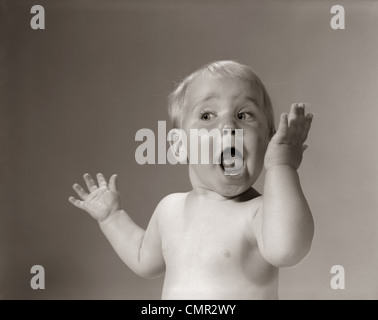 1960s PORTRAIT BABY WITH HANDS IN AIR AND EYES & MOUTH WIDE OPEN Stock Photo