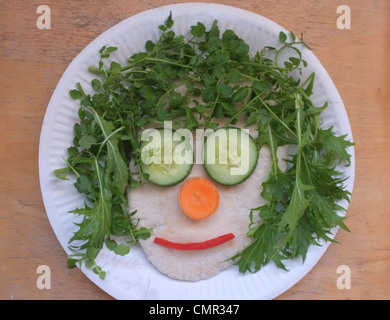 A child vegetable face on a paper plate Stock Photo