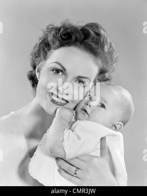 1950s PORTRAIT OF MOTHER HUGGING BABY LOOKING AT CAMERA Stock Photo