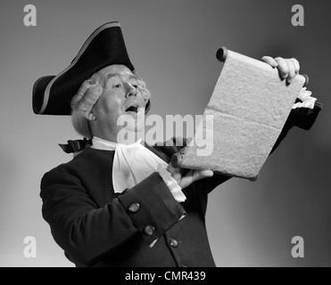 1960s 1970s MAN IN COLONIAL TOWN CRIER COSTUME READING OFF OF SCROLL Stock Photo