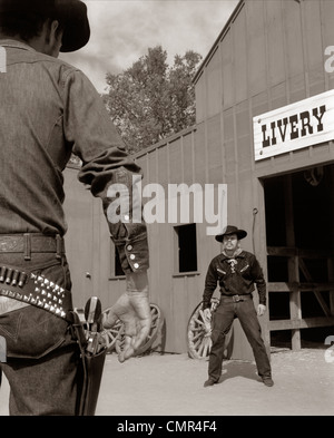 1950s 1960s TV COWBOYS IN FRONT OF LIVERY STABLE READY TO DRAW PISTOLS IN GUNFIGHT Stock Photo