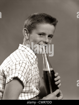 1950s SMILING BOY DRINKING CARBONATED BEVERAGE FROM SODA POP BOTTLE WITH STRAW Stock Photo