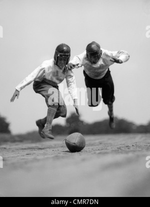 1930s PAIR OF BOYS IN KNICKERS & LEATHER HELMETS RACING TO DIVE ON FOOTBALL Stock Photo