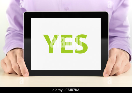 Manager holding tablet pc with "YES" text on screen. Stock Photo