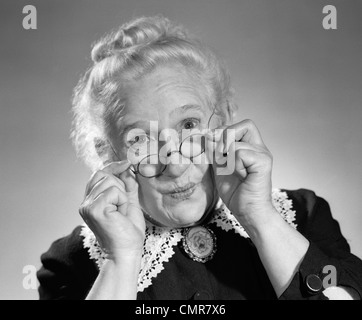 1950s PORTRAIT OF SMILING OLD LADY HOLDING HER ANTIQUE WIRE FRAME GLASSES Stock Photo