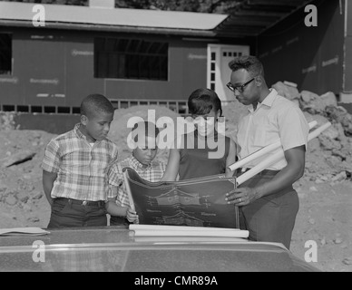 1960s AFRICAN AMERICAN FAMILY LOOKING AT BLUEPRINTS NEW HOUSE CONSTRUCTION Stock Photo
