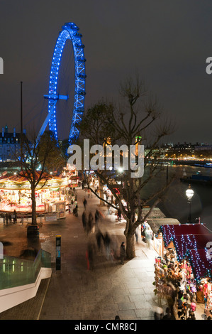 Night falls on a Christmas market on the Southbank and the London Eye in London, England. Stock Photo