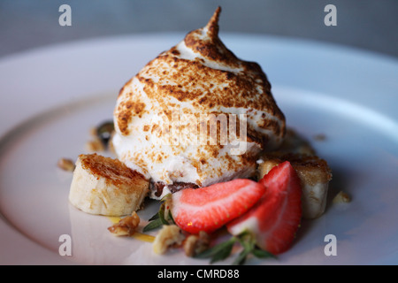 Baked Alaska is served with a bed of fruit. Stock Photo