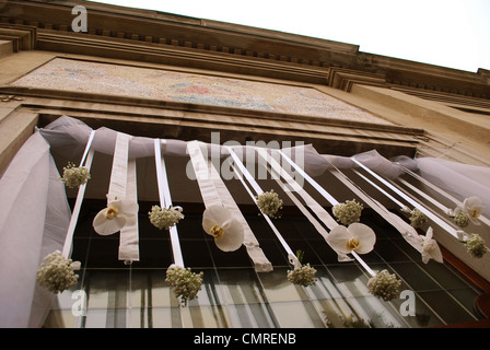 Hanging white wedding flowers on the front door of a church, sepia tone Stock Photo