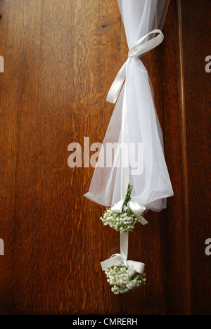 Hanging white wedding flowers on the front wooden door of a church Stock Photo